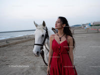 Woman in Red Dress with White Horse on Sandy Beach