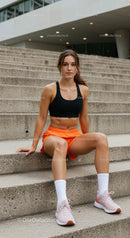 Athletic Woman in Orange Shorts Sitting on Modern Stairs