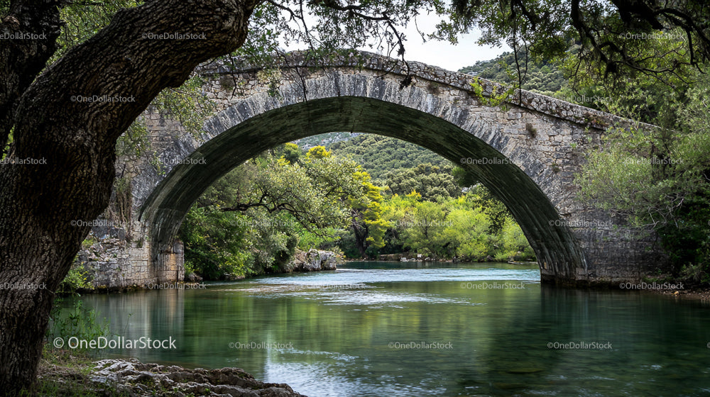 Stone Arch Bridge Over Serene River With Lush Greenery