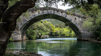 Stone Arch Bridge Over Serene River With Lush Greenery