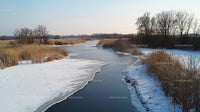 Frozen River with Snow-Covered Banks in Winter Landscape