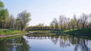 Tranquil River Scene with Reflective Bridge and Spring Foliage