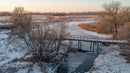 Serene Winter Landscape with Frozen River and Wooden Bridge