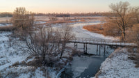 Serene Winter Landscape with Frozen River and Wooden Bridge