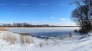 Frozen Lake with Snow-Covered Shoreline and Blue Sky