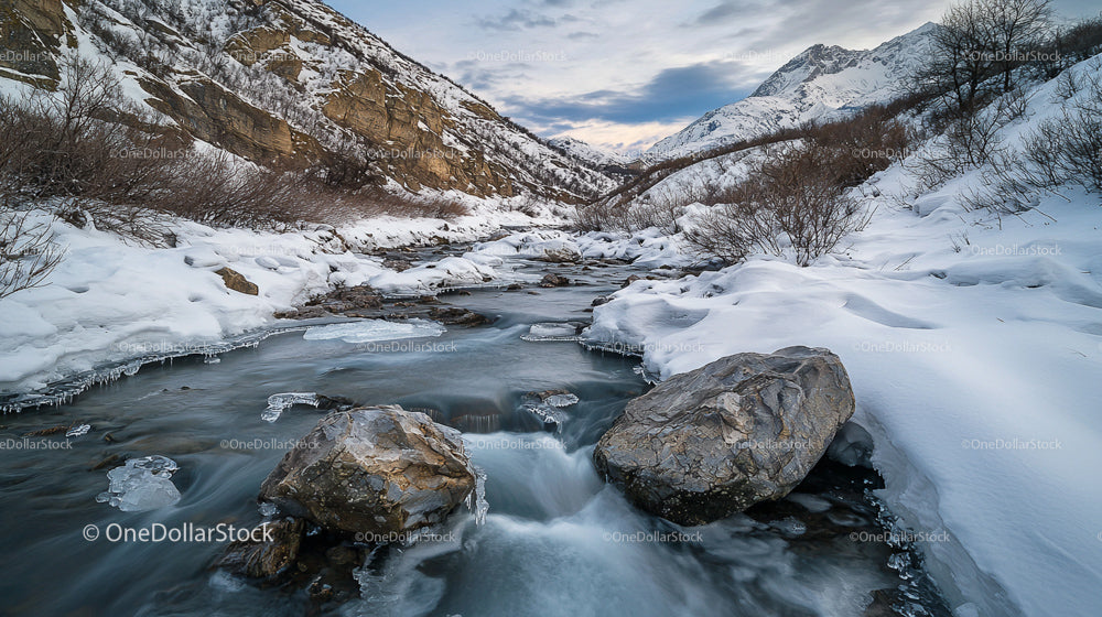 Serene Winter Alpine Landscape with Snowy Mountains and Stream