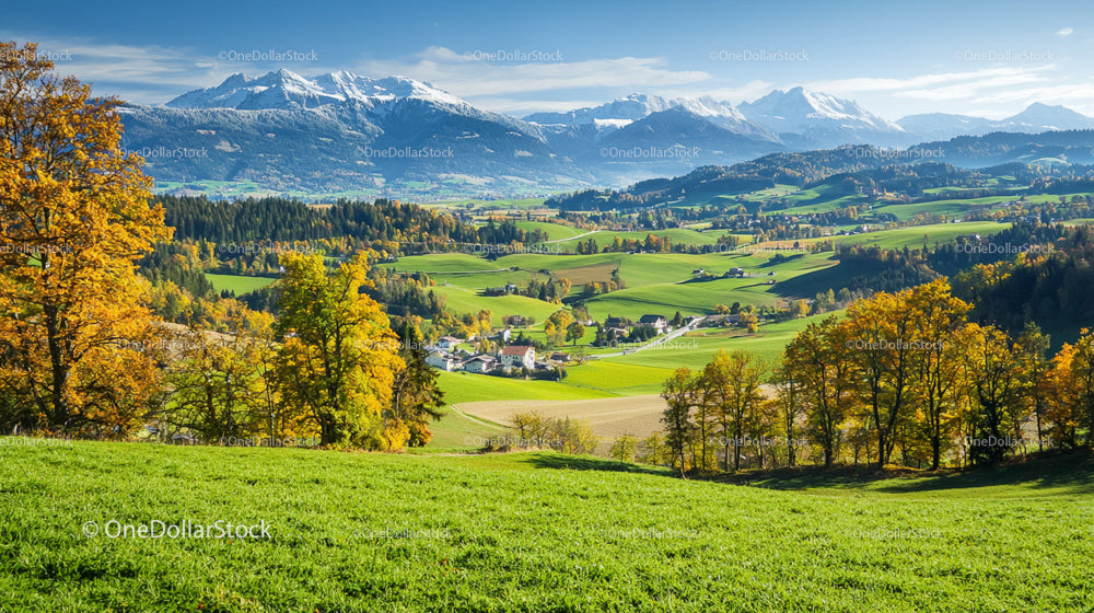 Autumn Landscape with Snow-Capped Mountains and Rolling Hills