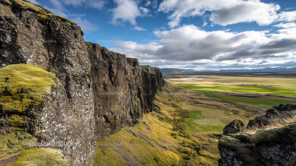 Mossy Cliffs and Vast Plains Beneath a Dramatic Sky