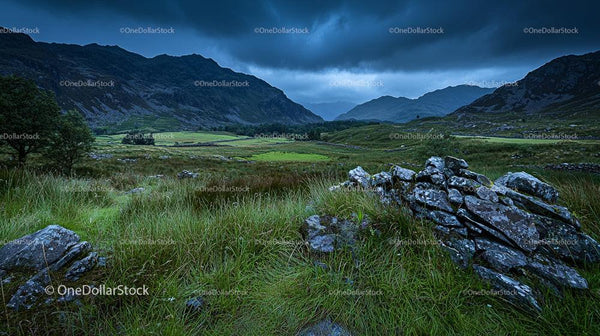 Moody Mountain Landscape with Lush Green Fields and Rocky Terrain