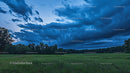 Dramatic Storm Clouds Over Lush Green Meadow at Twilight
