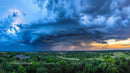 Dramatic Storm Clouds Over Verdant Landscape at Sunset