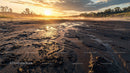 Golden Sunset Over a Muddy Riverbank with Dramatic Sky