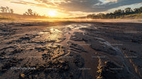 Golden Sunset Over a Muddy Riverbank with Dramatic Sky