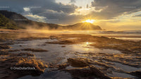 Golden Sunrise Over Rocky Beach with Misty Morning Atmosphere