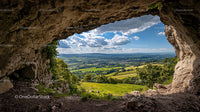 Scenic View from a Rocky Cave Overlooking Green Countryside