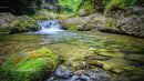 Serene Waterfall Flowing Through Moss Covered Rocks