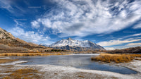 Snowy Mountains and Frozen Lake Under Blue Sky