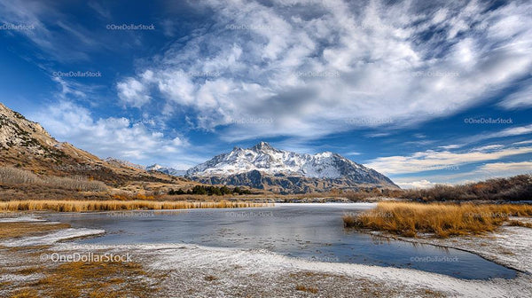 Snowy Mountains and Frozen Lake Under Blue Sky