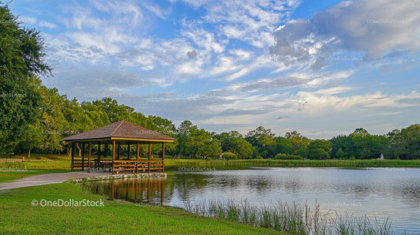 Scenic Lakeside Pavilion with Lush Greenery and Blue Skies