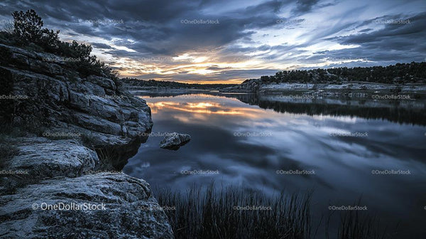 Tranquil Sunset Over Reflective Lake with Rocky Shoreline
