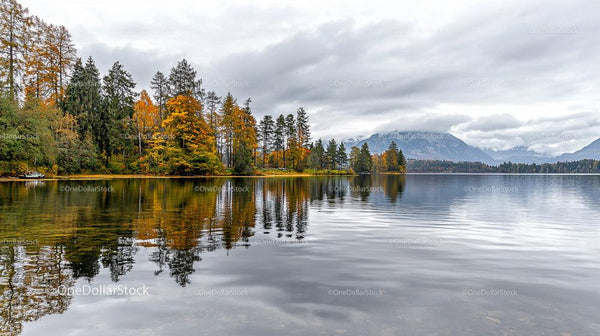 Serene Lake with Autumn Foliage and Misty Mountains