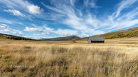 Rustic Barn in Open Field Under Blue Autumn Sky