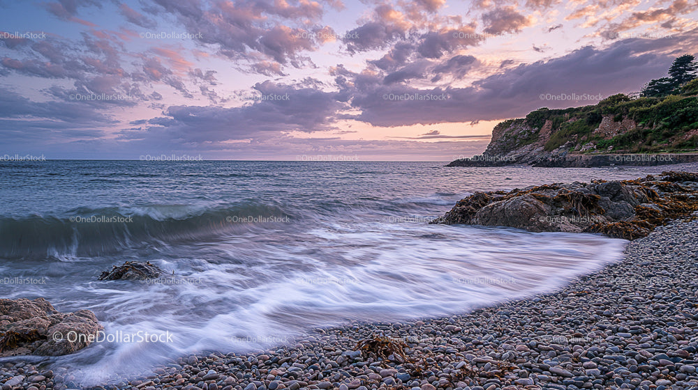 Peaceful Coastal Sunset with Waves and Rocky Shoreline