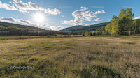 Sunlit Meadow with Rolling Hills and Blue Sky Vista