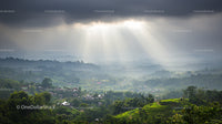 Sun Rays Breaking Through Clouds Over Lush Green Hills