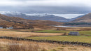 Stone Cottage Amidst Rolling Hills and Snow-Capped Mountains