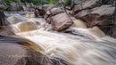 Powerful Waterfall Flowing Over Rugged Rocks in Lush Wilderness