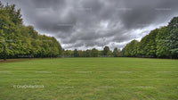 Expansive Green Field Under Dramatic Overcast Sky