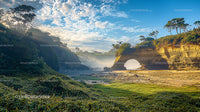 Scenic Coastal Archway with Lush Greenery and Blue Skies