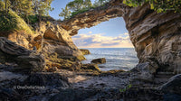 Natural Rock Arch Overlooking Serene Ocean at Sunset