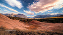 Majestic Mountain Range with Red Rock Formations under Dramatic Sky