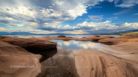 Dramatic Sky Over Rocky Shoreline with Reflective Water