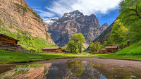 Scenic Alpine Valley with Wooden Cabins and Majestic Mountains