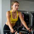 Focused Woman Cycling in Gym Wearing Yellow Sports Bra