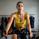 Determined Young Woman Cycling Indoors in Yellow Sports Bra