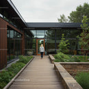 Woman Walking by Modern Glass Building Surrounded by Greenery