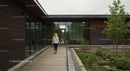 Woman Walking Towards Modern Office Building with Greenery
