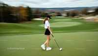 Woman on Golf Course with Club Walking on Green Fairway