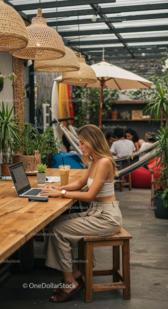 Kobieta pracująca na laptopie w kawiarni na świeżym powietrzu z roślinami