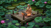 Man Meditating with Laptop on Serene Lotus Pond Platform