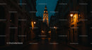 Illuminated Cobblestone Street with Historic City Tower