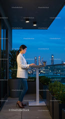 Businesswoman Working on Laptop on City Balcony at Night