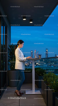 Businesswoman Working on Laptop on City Balcony at Night
