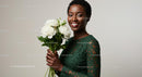 Smiling Woman in Green Lace Dress Holding White Flowers