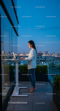 Businesswoman Working on Rooftop Balcony with City Skyline View