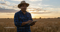 Farmer Using Tablet in Golden Wheat Field at Sunset